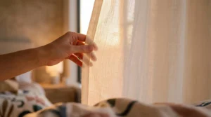 Une main effleurant délicatement un rayon de lumière chaude dans une chambre tamisée, symbolisant l'ouverture de l'imagination intime